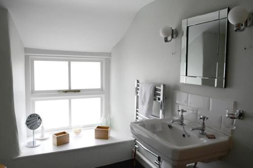 a bathroom with a sink and a mirror and two windows at Spring Cottage,Gorgeous and Hi-spec in Kilkhampton