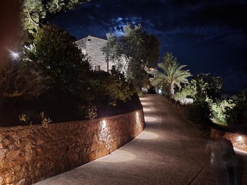 a walkway with a stone wall at night at Villa L'Arbousière in Porto-Vecchio
