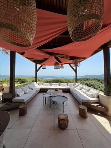 a large room with tables and chairs and a view of the ocean at Villa L'Arbousière in Porto-Vecchio