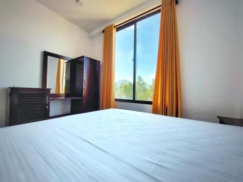 a bedroom with a white bed and a large window at Catch Up Dambulla in Dambulla