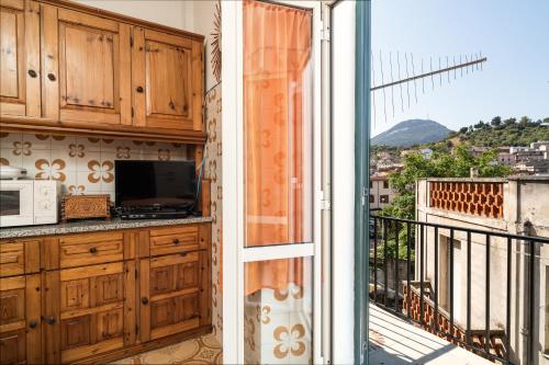 a kitchen with wooden cabinets and a balcony with a view at Casa Rachele in Dorgali