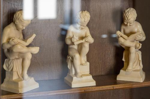 a shelf with three statues of children reading at Casa Rachele in Dorgali