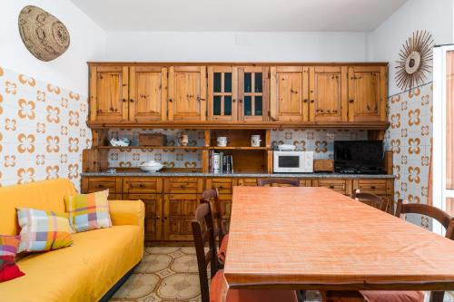 a kitchen with a yellow couch and a wooden table at Casa Rachele in Dorgali