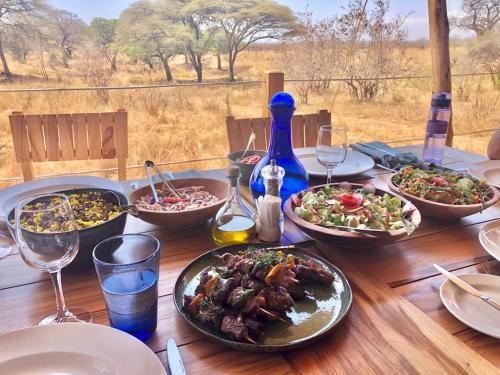 a wooden table with plates of food on it at Olkeri Camp in Olmotoni