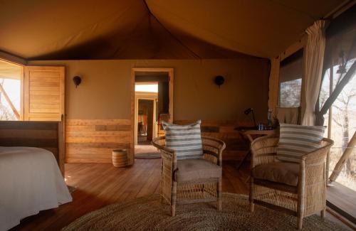 a bedroom with a bed and chairs in a tent at Olkeri Camp in Olmotoni
