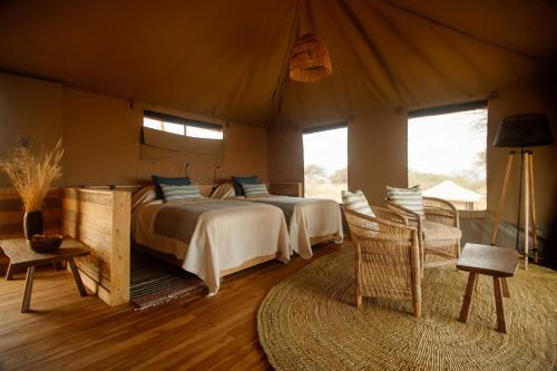 a bedroom with two beds and chairs in a tent at Olkeri Camp in Olmotoni