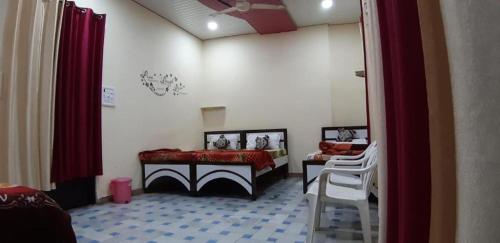 アムリトサルにあるBlue eye Backpackers Hostelのベッド、テーブル、椅子が備わる客室です。