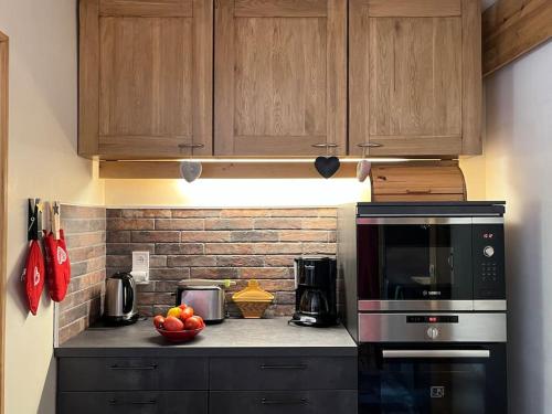 une cuisine avec des armoires en bois et un micro-ondes noir dans l'établissement Le Cocon des Cimes 2 à 5 pers., à La Plagne Tarentaise