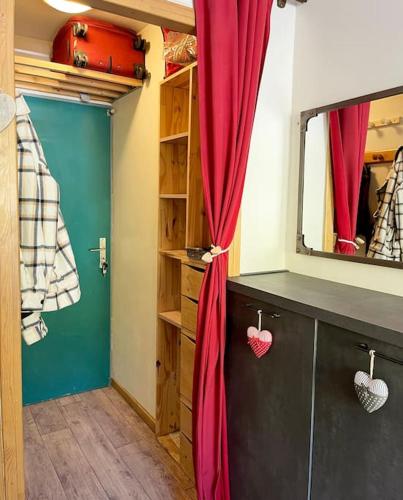 Cette chambre comprend un rideau rouge et un miroir. dans l'établissement Le Cocon des Cimes 2 à 5 pers., à La Plagne Tarentaise