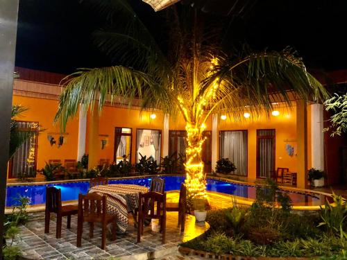 a patio with a table and a palm tree with lights at Rosa Garden in Ninh Binh