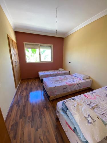 um quarto com três camas e uma janela em Villa haut standing dans une résidence fermée em Zaouia Sidi Rahkal