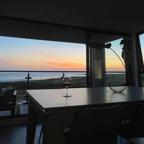 a wine glass sitting on a table in front of a window at Seafront apartment with spectacular views in Porthcawl