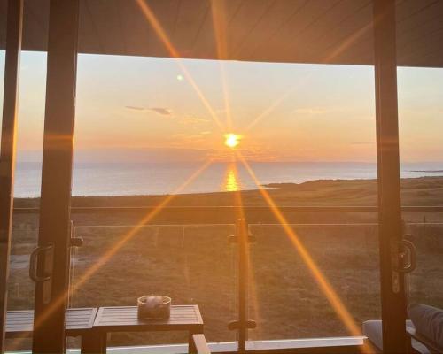 a view of the sunset from a room with a window at Seafront apartment with spectacular views in Porthcawl