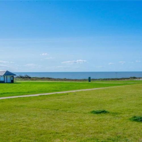 a field of green grass with a building in the distance at Seafront apartment with spectacular views in Porthcawl