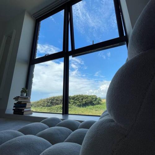 a room with a window with a couch and books at Seafront apartment with spectacular views in Porthcawl