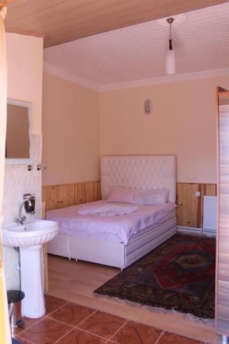 a bedroom with a white bed and a sink at Sultan Pansion Bird Paradise in Ovaciftlik