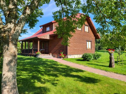 una gran casa de madera en un césped verde en Antano Budriaus sodyba, en Lopaičiai