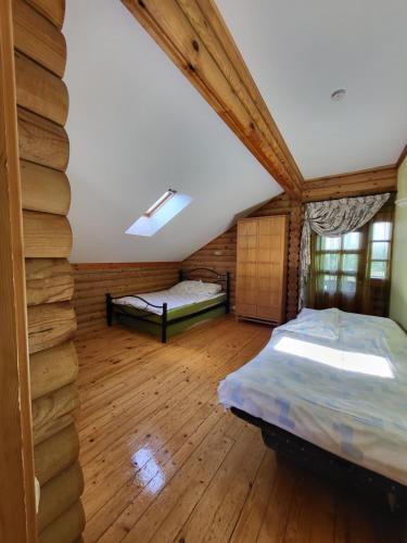 1 dormitorio con 2 camas en una cabaña de madera en Antano Budriaus sodyba, en Lopaičiai