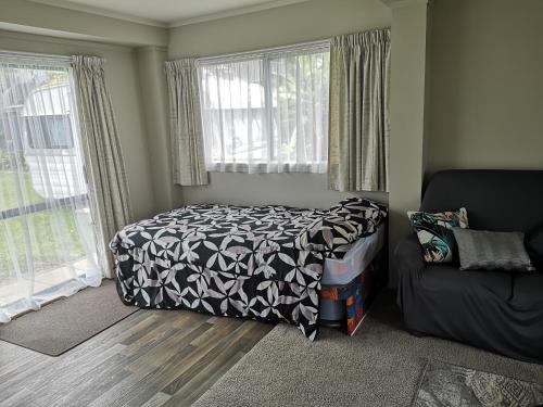 a bedroom with a bed and a couch and windows at Houhora Harbour Haven in Pukenui
