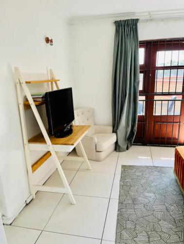 ein Wohnzimmer mit einem Schreibtisch und einem TV darauf in der Unterkunft Petalsoft in Pretoria