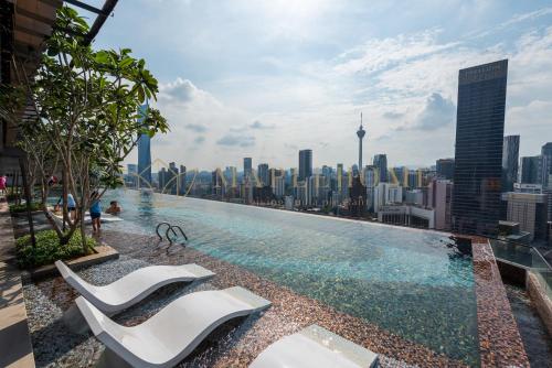 een zwembad met 2 stoelen en een skyline van de stad bij Axon Premier Suites Kuala Lumpur in Kuala Lumpur