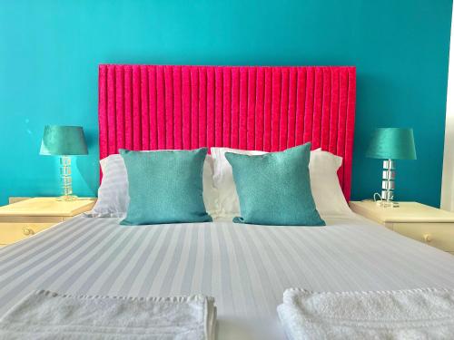 a large bed with a red headboard and two lamps at Gorgeous Sea View Two Bed Apartment - Close to Beach with Free Parking in Bournemouth