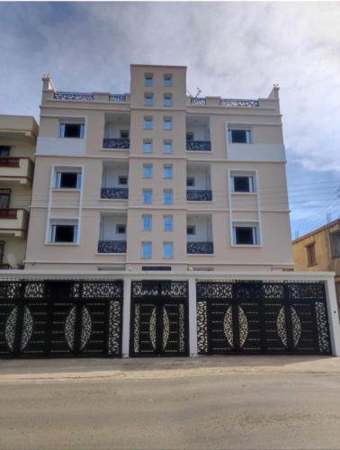 a tall white building with a fence in front of it at Résidence Le Figuier Marako, Tizi-Gheniff 