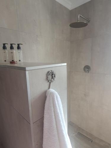 a bathroom with a white towel and a shower at Spindrift Seaside Accommodation in Wilderness