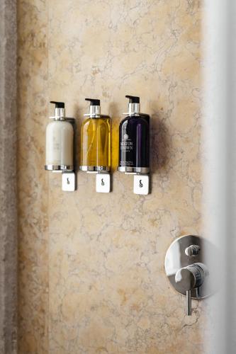 a bathroom wall with three soap dispensers on a wall at The House on the Pink Street in Lisbon in Lisbon