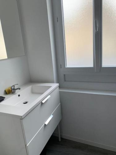 een witte badkamer met een wastafel en een spiegel bij Studio en centre ville d'Argentan in Argentan