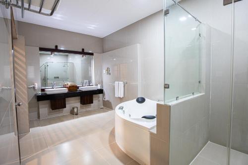 La salle de bains est pourvue d'une baignoire et d'une douche en verre. dans l'établissement Club Palm Bay, à Marawila