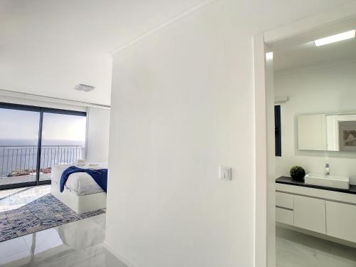 una camera da letto bianca con vista sull'oceano di Casa dos Amores by LovelyStay a Calheta
