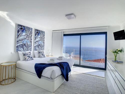 ein Schlafzimmer mit einem großen Bett und einem großen Fenster in der Unterkunft Casa dos Amores by LovelyStay in Calheta