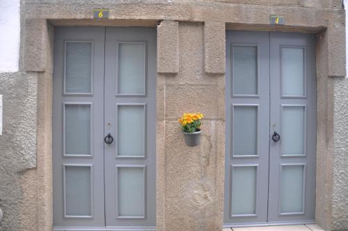 twee grijze deuren met een bloempot aan de zijkant van een gebouw bij Casinhas de S. Francisco T2 Azeitona by LovelyStay in Freixo de Espada à Cinta