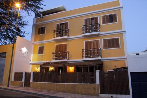 a yellow building with balconies and a fence at Kira's Boutique Hotel in Mindelo