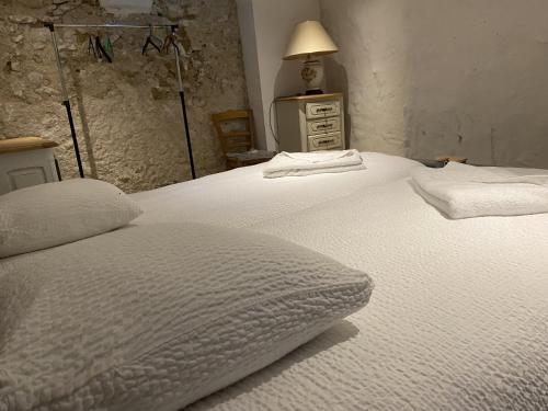 a bedroom with two beds with white sheets and a lamp at Gite des vieilles pierres in Seigy
