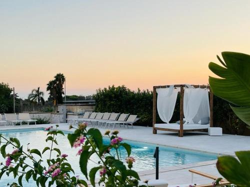 a swimming pool with chairs and a wedding arch at Hotel Posidonia in Porto Cesareo