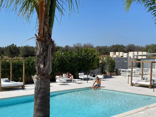 a woman in a swimming pool next to a palm tree at Hotel Posidonia in Porto Cesareo