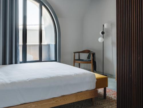 um quarto com uma cama, uma janela e uma cadeira em Lisbon Five Stars Alcântara Lofts em Lisboa