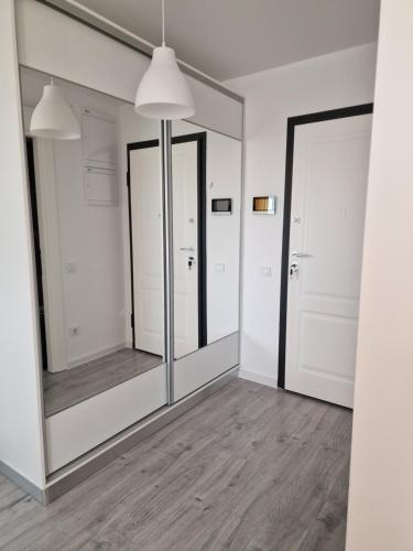 een spiegel in een kamer met witte muren en houten vloeren bij Luxury Grey Apartments in Iaşi