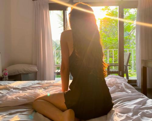 a woman sitting on a bed in front of a window at Lakmini Lodge Sigiriya in Sigiriya