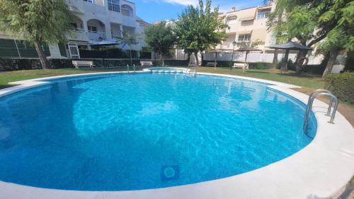 a large blue swimming pool in front of a building at Bungalow sol y playa in El Campello