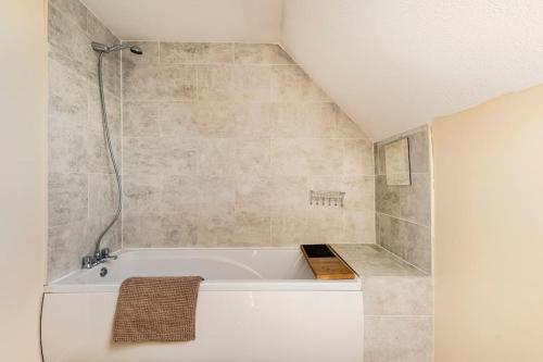 a white bath tub in a bathroom with a shower at Charming Entire 2-Bedroom House in Milton Keynes in Milton Keynes