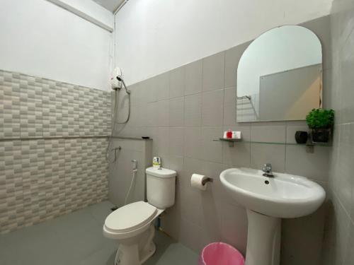a bathroom with a toilet and a sink and a mirror at Nokhook House in Trang