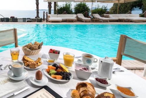 a table with breakfast food next to a swimming pool at Hotel Villa Capri in Gardone Riviera