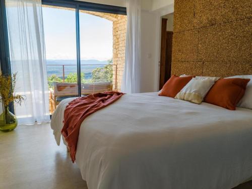 a bedroom with a large white bed with a large window at Villa L'Arbousière in Porto-Vecchio