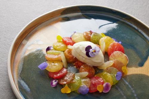 a plate of fruit salad with whipped cream and flowers at Hotel Palafitte in Neuchâtel
