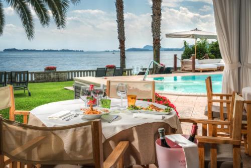 a table with food and drinks next to a swimming pool at Hotel Villa Capri in Gardone Riviera