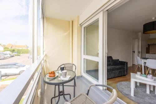 - un balcon avec une table et un canapé dans l'établissement L'Ancre Marine - Appt à 100m de la plage, à Courseulles-sur-Mer
