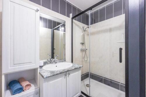 une salle de bain blanche avec un lavabo et une douche dans l'établissement L'Ancre Marine - Appt à 100m de la plage, à Courseulles-sur-Mer
